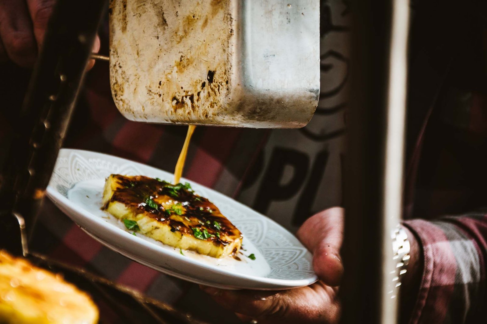 Grilled caramelised pineapple with fresh herbs, sauce poured from a camping mess tin